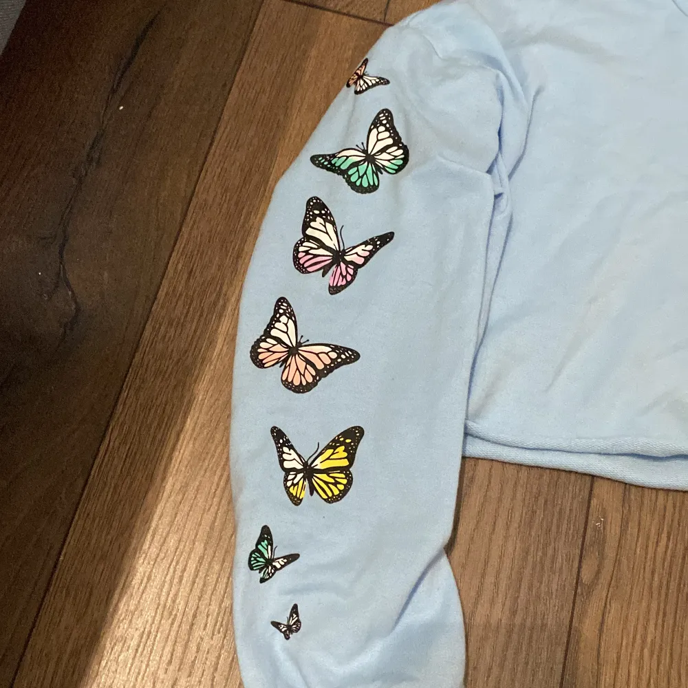 En ljusblå tröja med fjärilar på en liten fläck längst ner på tröjan men syns inte när man har på den men bara för fläck n så sänker jag priset.. Toppar.