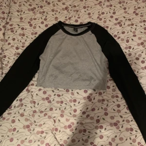 Croppad tröja - En svart och grå, croppad tröja från SHEIN. Jag har bara använt den en gång och den är i något ”glansigt” och mjukt material❤️🥰