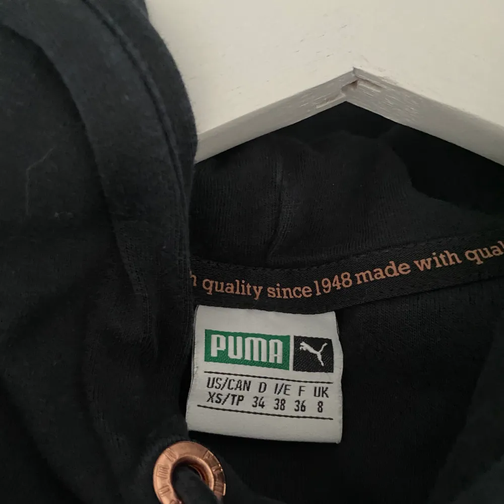 Svart Puma hoodie med guld detaljer i bra skick. Storlek 36 men passar även på 38/40. Hoodies.