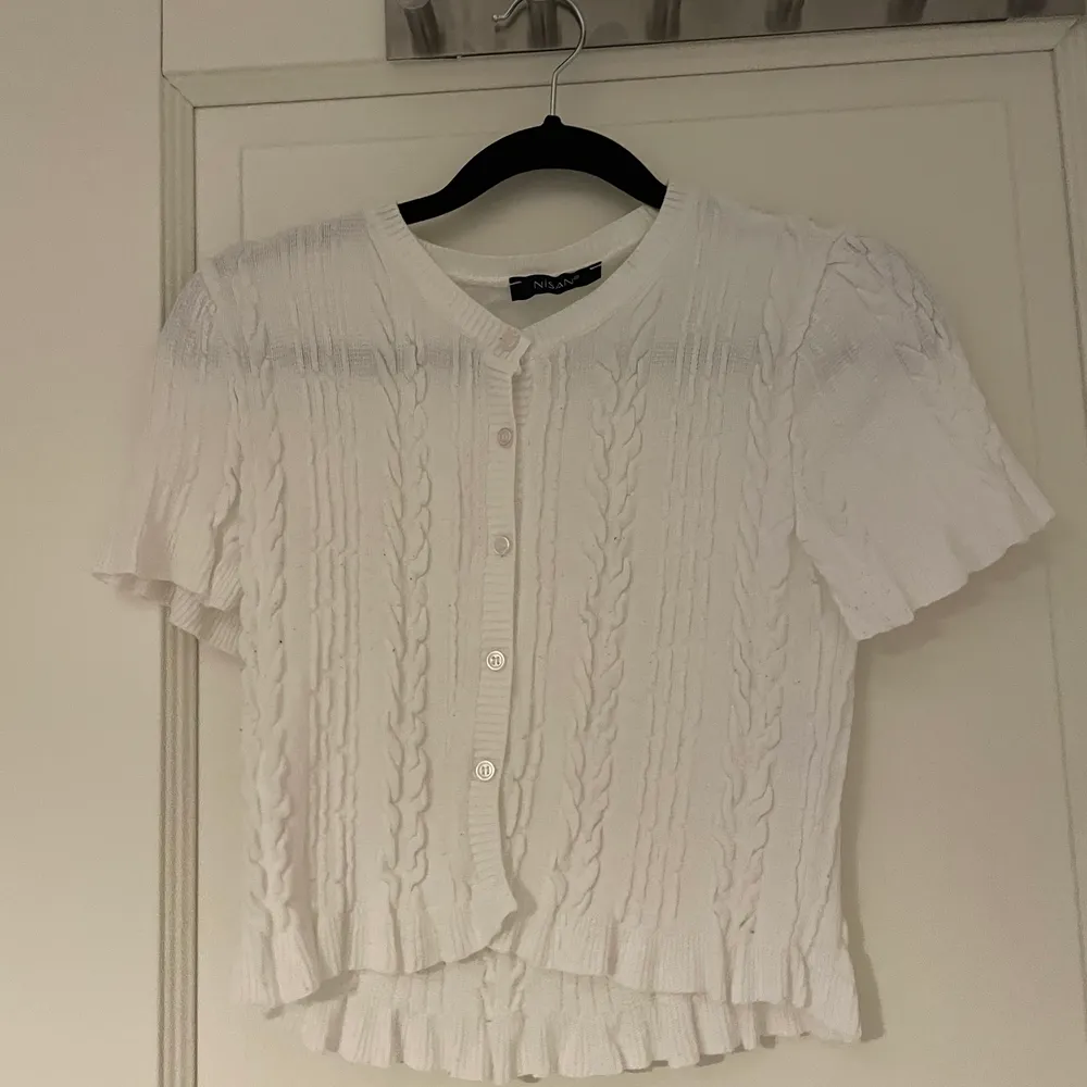 T-shirten är med knappar och har väldigt fina detaljer som man kan se på bilden och volanger på slutet,passar jätte fint med lågmidjande jeans och bara använd 2 gånger. Toppar.