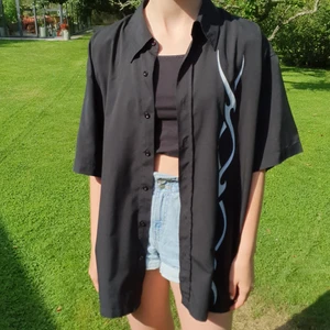 Svart kortärmad skjorta med vitt mönster - Svart kortärmad skjorta med vitt mönster/tryck. Storlek XL men sitter på mig som har xs-s som på första bilden. Säljer då den är ej min stil längre. Köpt på Röda Korset, ej använd särskilt mycket så nästan som ny.