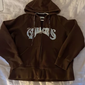 Hoodie y2k - Säljer denna fina hoodie, köpt second hand för 400kr. Säljer för 200kr +frakt, om inte de blir budgivning. Står att den är storlek XL men den är för liten för mig som bär M/S. Den är storlek S/XS skulle jag säga. Jag är 166cm. Möter i Bromma plan och TC