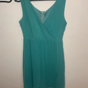 Turkos blå wrap dress - Färgen på klänningen är turkos blå nästan grön kan man säga, den är underbar och ser ut som en wrap-topp tillsammans med en luftig kjol! Du får den nu 50% off