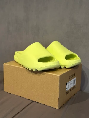 Yeezy slide Glow green - Endast testade 1 gång Og box ingår. Storlek 44 1/2. Men är lite mindre i storlek.