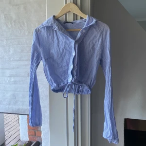 Blus/ skjorta från Brandy Melville - Kort skjorta från brandy Melville! Som ny - nästan aldrig använd.  Hittar tyvärr inte vilken storlek det är men skulle säga att den passar som storlek xs.   Jag kan mötas upp i Stockholm city eller norr om stockholm, annars får köparen stå för frakten!😊