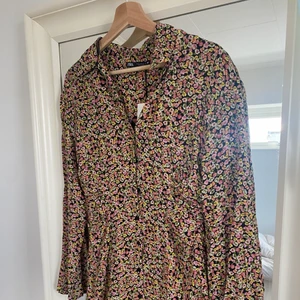 Blommig kort klänning zara  - Superfin blommig sommarklänning från Zara som är helt oanvänd. Den är kort, figursydd vid midjan och har en tenniskrage 💗🌼