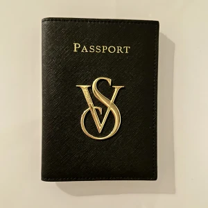 Passfodral från Victoria’s Secret - Passfodral i svart saffianoläder och gulddetaljer från Victoria’s secret. Fodralet kan skickas om köparen står för emballage (Postnords blå kuvert) + frakt