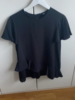 svart zara blus - en fin svart blus från zara med en fin volang. Kan användas till det mesta och är helt oanvänd.(nypris 399kr)