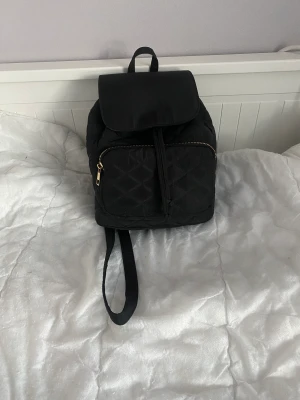 Svart liten ryggsäck  - Säljer min svara lilla väska köpte den för några månader sen har bara använt den i några dagar sen slutade jag för att jag tyckte inte om designen säljer den för 250kr köpte den från Glitter 
