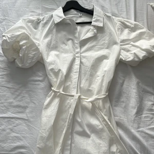 Skjortklänning  - Vit skjortklänning med band i midjan och puffärmar. (Om du vill se plagget på skriv privat)