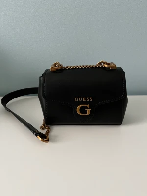 Guess väska - Guess väska, använd 1 gång, i nyskick.   Mått: Höjd 15cm  Längd 17cm Vidd 8cm