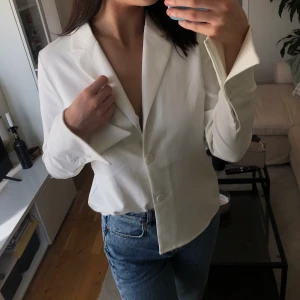 Vit Skjorta HossxNakd - Superfin och elegant vit v-ringad skjorta från Hoss kollektion med NaKd. Använd fåtal gånger. Spetsiga utstickande ärmar. Storlek 40.