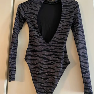 Glittrig body från HM - Gittrig body från Hm med öppen rygg, aldrig använts, köparen står för frakt.