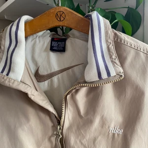 Nike Jacka Vintage - FINNS KVAR! Vintage Nike jacka i beige färg, perfekt för hösten. Storlek M i riktigt bra skick. Feta detaljer som kragen och broderade loggor. Frakt tillkommer 💛(Lägger upp igen då någon klickade köp nu på förra)