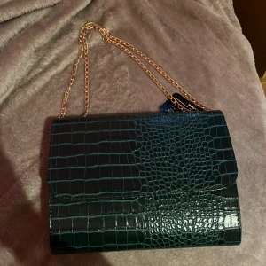 Grön axelremsväska - Söt grön axelremsväska som kan användas som kuvertväska. Väskan är är i nytt skick då det har aldrig använts.