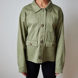 Silkig grön jack-skjorta  - En boxig skjorta i jack-modell i silkigt material med fickor. Funkar för S-M