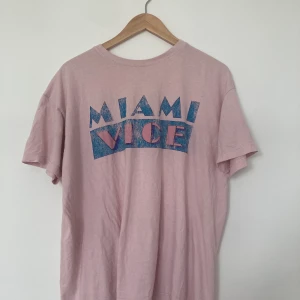 Miami Vice-tröja - Jätteskön babyrosa t-shirt med Miami Vice-tryck! Står ingen storlek men skulle gissa S-M :)