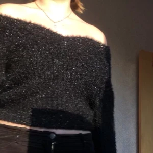 Off shoulder glittrig stickad tjocktröja - Glittrig stickad off shoulder tröja i mjukt material- inte stickig. Bekväm och passar många storlekar. Går in i midjan- kan användas som magtröja eller vanlig längd. 