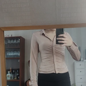 Figursydd tröja/skjorta - En helt oanvänd tröja/skjorta. Glansigt tyg med knappar. Köpt på HM i storlek S