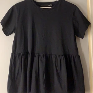 T-shirt med volang - Säljer en super gullig svart t-shirt med volang ifrån lager 157. Aldrig använd. Storlek XS men passar även S