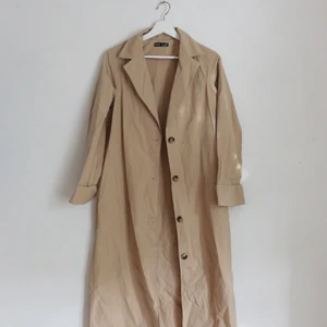 Trenchcoat - Köpte denna för något år sen men säljer då den ej kommit till användning. Passar bra på mig som är 170cm.   Helt i nyskick.  Katt finns i hemmet. 