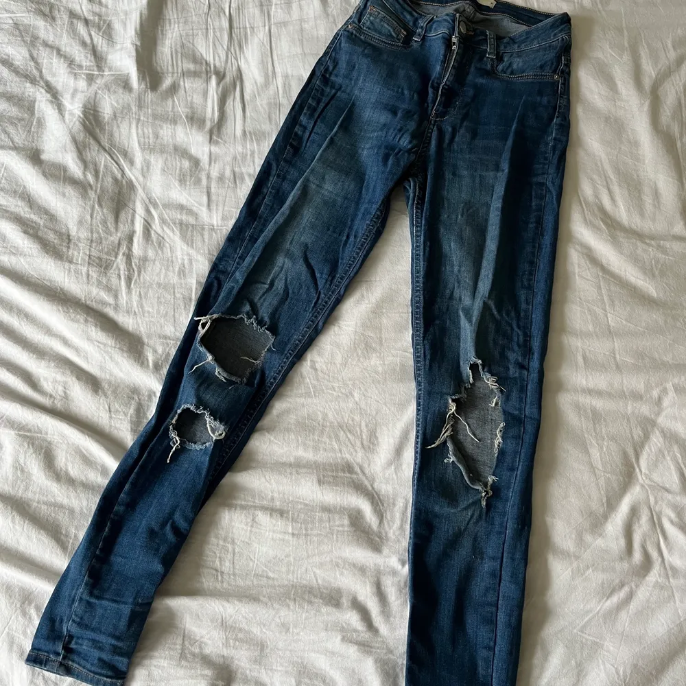 Ett par blåa slim jeans med slitningar från Ginatricot i storlek M.. Jeans & Byxor.