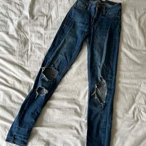 Ett par blåa slim jeans med slitningar från Ginatricot i storlek M.