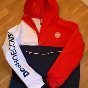 DC SHOES JACKA / ANORAK - Riktigt skön DC SHOES jacka/anorak, den har en stor magficka med dragkedja och fickor för händerna. Luvan har en liten skärm på sig och den står emot regn rätt bra. Frakt tillkommer med 66kr 