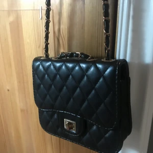 Svart läder (ej äkta) väska - Medel lång, okej skick, guld detaljer på axel bandet! Kan mötas inom/nära Borlänge.