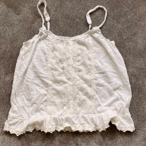 Vitt linne med spets  - Ett vitt linne från hollister i storlek M. Spets på magen med blommor!