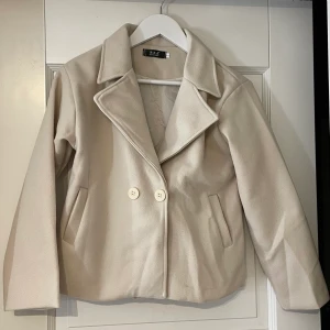Kort kappa - Superfin beige kappa i storlek S, men är väldigt liten så skulle säga mer som en XS! Aldrig använd. Buda från 300 exklusive frakt 🤎
