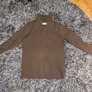 Samsøe Samsøe half zip strlk S - Plagget är i mycket bra skick och är endast använd 2 gånger. Säljer den då den inte passade mig så bra. Half zippen är fint stickad och i en mycket fin brun färg som passar väldigt bra nu till sen höst/vinter! 