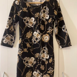 Klänning - Svart klänning med guldiga detaljer .  Använt 1-2 gånger . Klänningen är i nyskick 