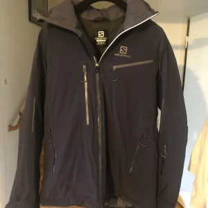 Skidjacka Salomon - Skidjacka från Salomon i storlek Small. Mycket bra skick endast använd 4 dagar. Har två bröstfickor, två ”vanliga fickor”, innerficka med dragkedja, påsinnerficka, ärmficka med plats för liftkort och ventilation i armhålorna. 