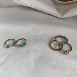 ringar i guld/silver och brons!  - 1: 10kr  två ringar i brons färgat material med blå stenar från Åhléns. väl använda så rättså nötta, men ändå najs!  skick: 5/10  2: 15kr  tre guldringar, två av dem med vita stenar. nötta, under guldfärgen syns silver!   skick: 4/10