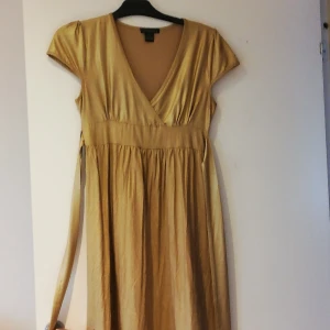 Klänning stl M.  - Ny Klänning storlek. M. I lätt stretchigt. Material. 100kr  plus fraktkostnad på 66kr tillkommer. Lite mattare guldfärg än bild avger tar gärna swish  