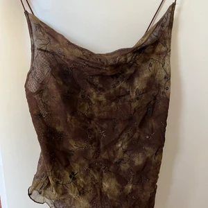 Brunt mesh-linne - Ett brunt meshlinne i olika nyanser med brunguldiga detaljer. Ryggen är seethrough men inte framsidan (material täcker insyn av brösten). Baksidan är lägre än framsidan och visar därmed övre ryggen. Bra skick! Säljs pga flytt och därmed utrensning av garderob. 