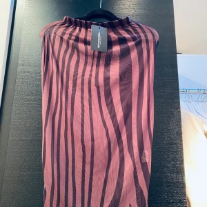 Kjol brun zebramönstrad - Zebramönstrad mesh kjol lång, går ner på halva vaden ca. Genomskinlig. Jättefin. Inte använd. Bilden lite missvisande, den är mörkbrun med svart zebramönster.