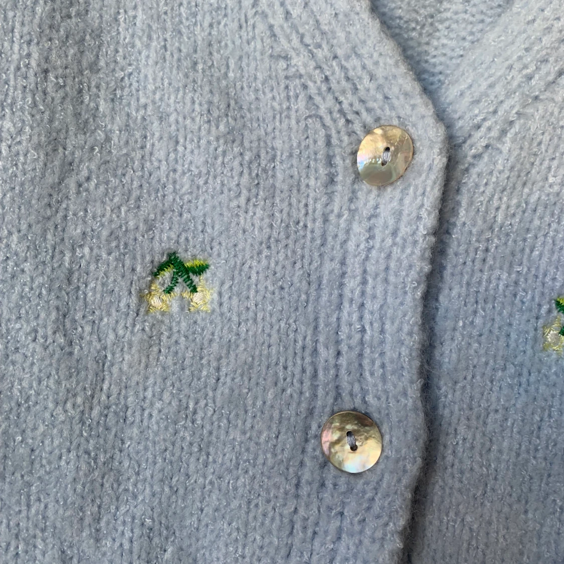 Ljusblå stickad kofta med blommor och snäckskalsknappar - 90