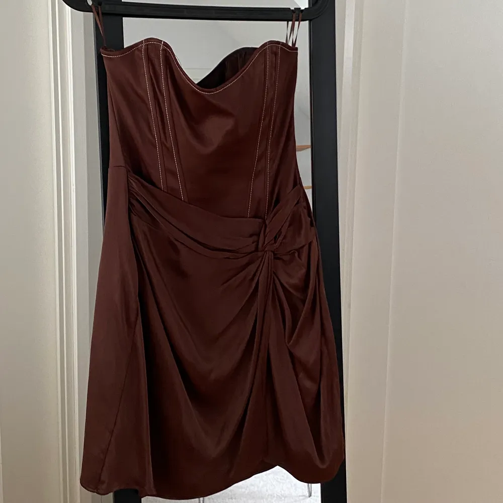 Oanvänd och eftertraktad festklänning i brunt sideninspirerande tyg🤎 prislapp sitter kvar! Det är storlek M men mer som en S. . Klänningar.