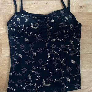 Svart topp med fina detaljer - Så fin satintopp med guldiga o bruna detaljer, köpt på humana men har inte kommit till använding. 