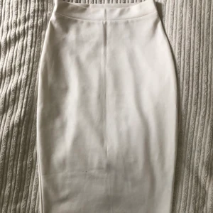 Vit midi pencil kjol - Nytt skick använd enbart 1 gång. Jättefin figursydd midi-längd till knäna med pencil modell. Strlk XS köpt från Nelly.