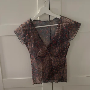 Meshtop från VILA - Y2k-inspirerad meshtop från VILA. Toppen är blommig och har en omlott-urringning. Superfin men har tyvärr inte fått någon användning av den💞💞