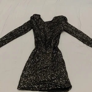 Rebecca Stella Glitterklänning - Svart glittrig klänning med djup ringning i ryggen. Rebecca Stella for Nelly. Använd 2 ggr, i nyskick. Relativt liten i storleken 