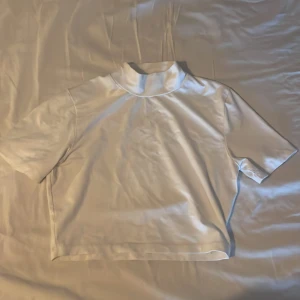 Topp - Säljer en vit, kort och tight T-Shirt med krage i strl M ifrån BikBok. Köparen står för frakten🤍