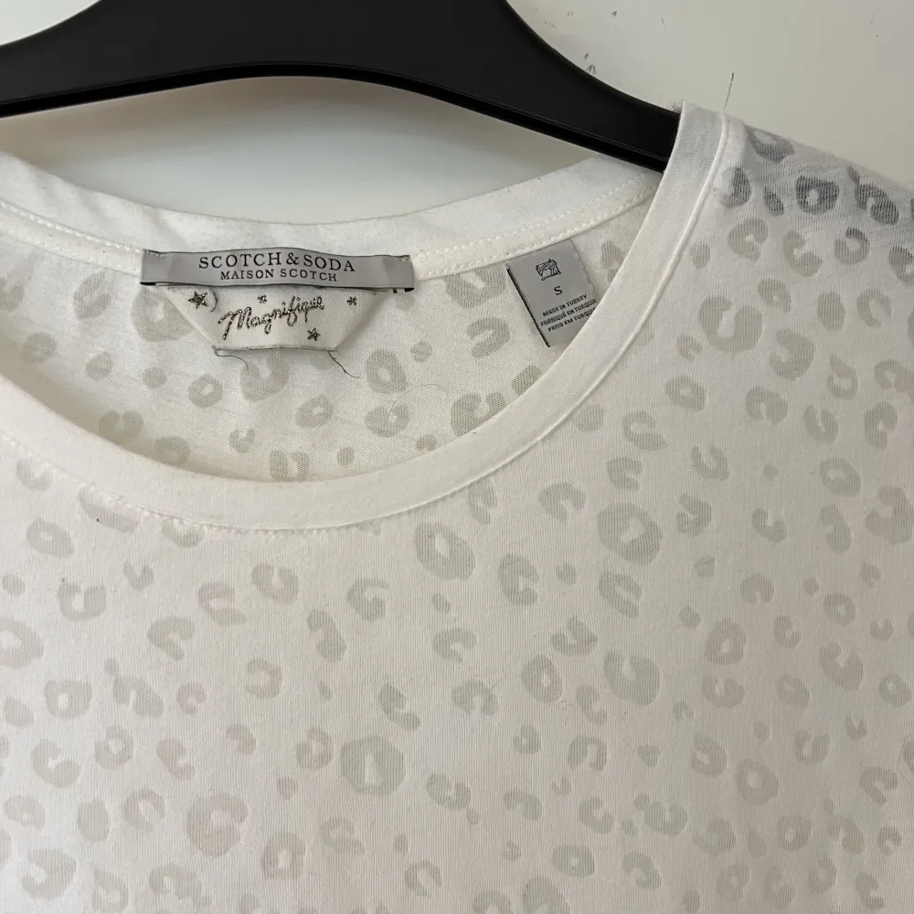 Vit t shirt från Scotch & Soda. T-shirten har ett leopardmöster som är lätt genomskinligt. T-shirts.