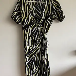 Gul svart och vit zebramönstrad omlottklänning som man knyter beroende på hur man vill ha den! Aldrig använd. Från newlook, säljes pga passar ej:(