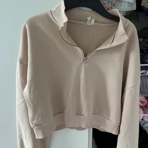 Zip hoodie beige - Beige half zip up hoodie från Nelly. Köpt för länge sen men sparsamt använd. Storlek M men liten i storlek. Mjukt material inuti.