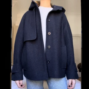 COS kappa  - Superfin kort kappa från COS i perfekt skick, perfekt inför våren💕. Marinblå färg, storlek xs (jag är 167 cm). Kappan har en luva, två fickor fram, en innerficka. Kappan stängs med knappar. Köpt förra året för 1800 kr, inga defekter! 💕