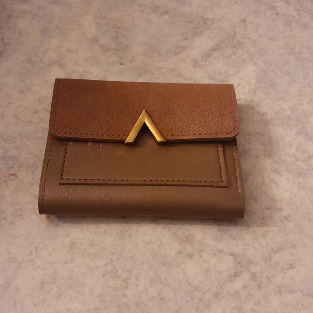 Brun liten plånbok med guldig dekor och knapp. Övrigt.